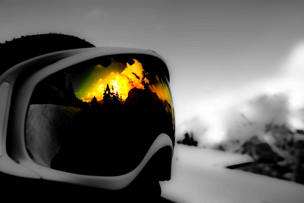 Prescription ski goggles reflecting a mountain sunset